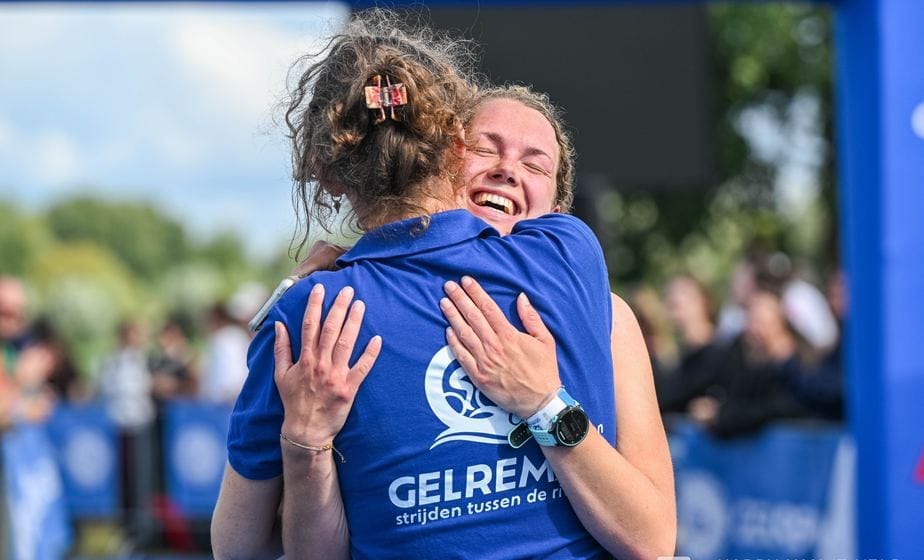 Twee vrouwen vallen elkaar in de armen na de finish