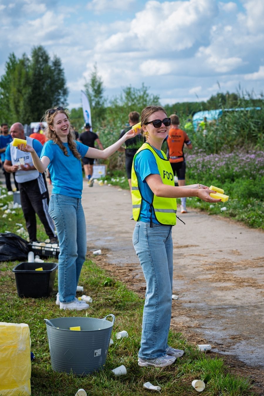 Twee vrijwilligers reiken bekers aan bij de voedingspost