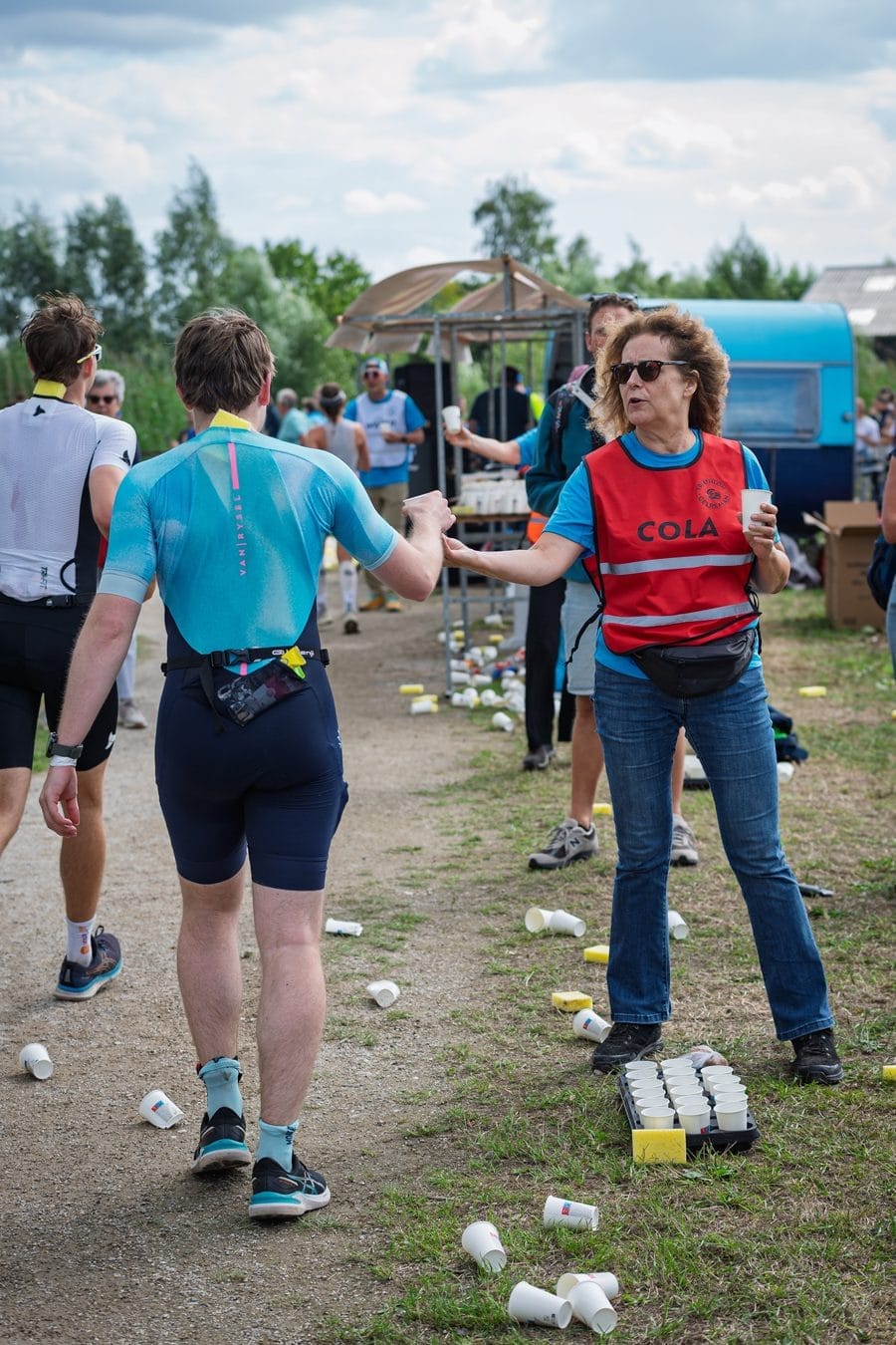 Vrijwilliger geeft een loper cola aan langs het parcours
